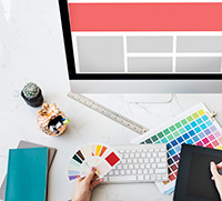 Color palettes being held by web design Ocean County professional in front of a monitor with a template on the screen