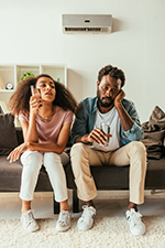 Couple sweltering on couch because of ineffective air conditioner repair in Mantoloking